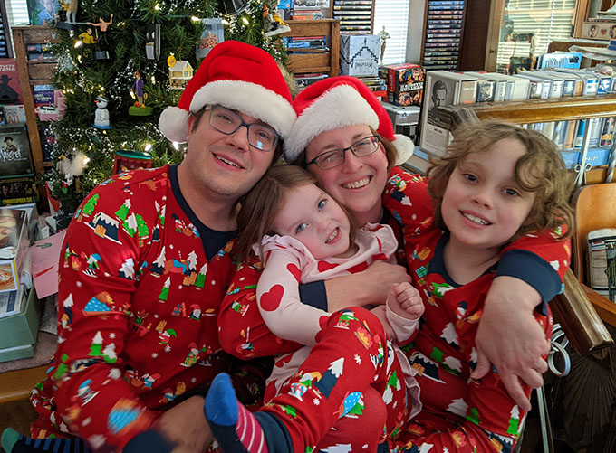 Children and grandchildren sitting in front of a Christmas tree.